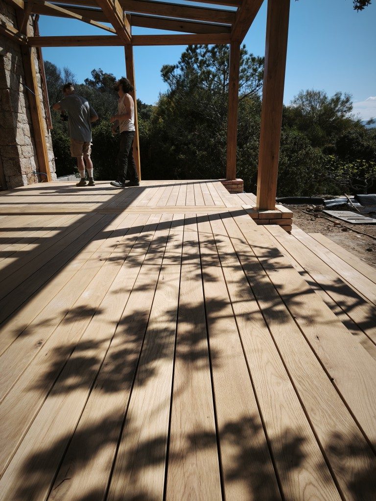 Schattenspiel auf dem Holzdeck unter der Pergola