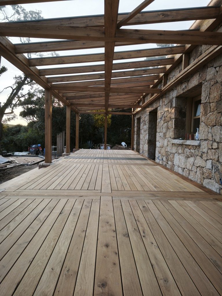 Terrassendeck unter der Pergola entlang des Steinhauses