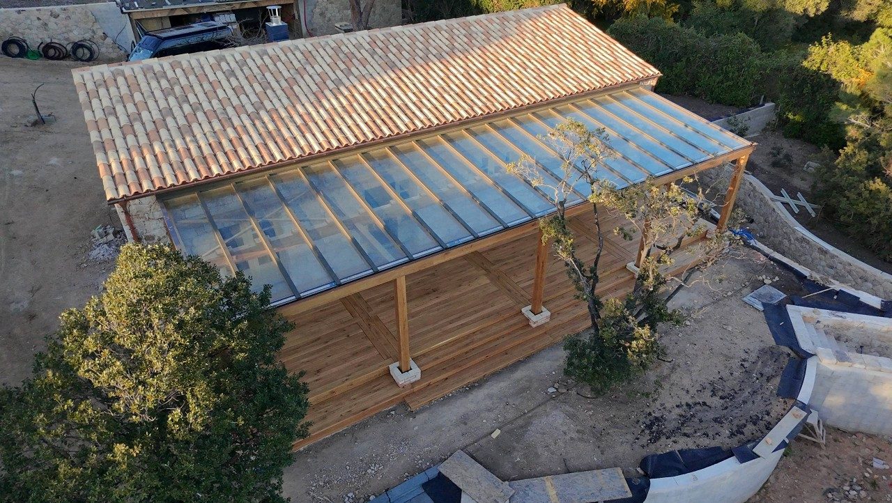 Luftaufnahme der Holzpergola mit Glasdach an einem Steinhaus auf Korsika