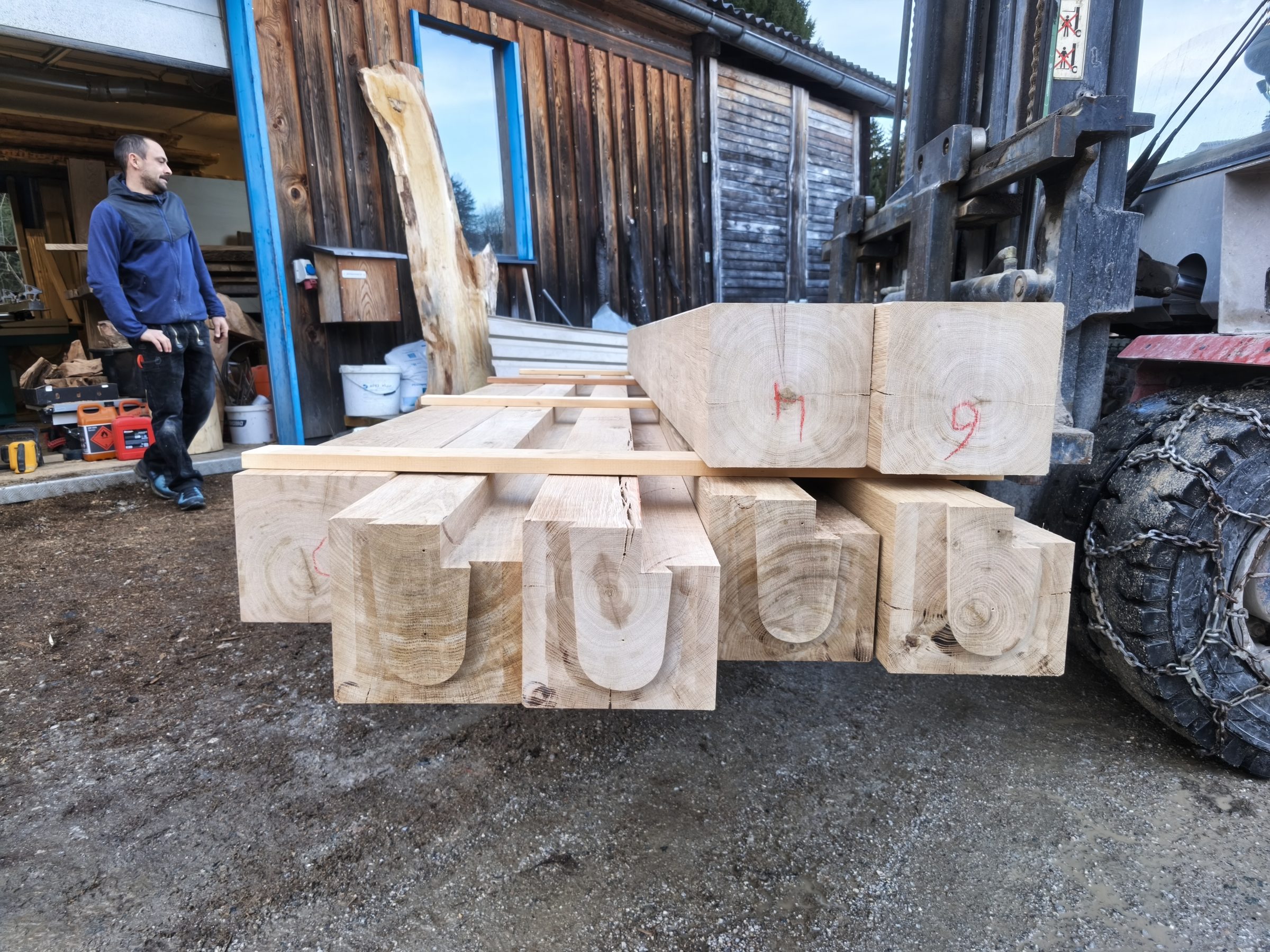 Abgebundene Massivholzbalken auf dem Stapler vor der Werkstatt