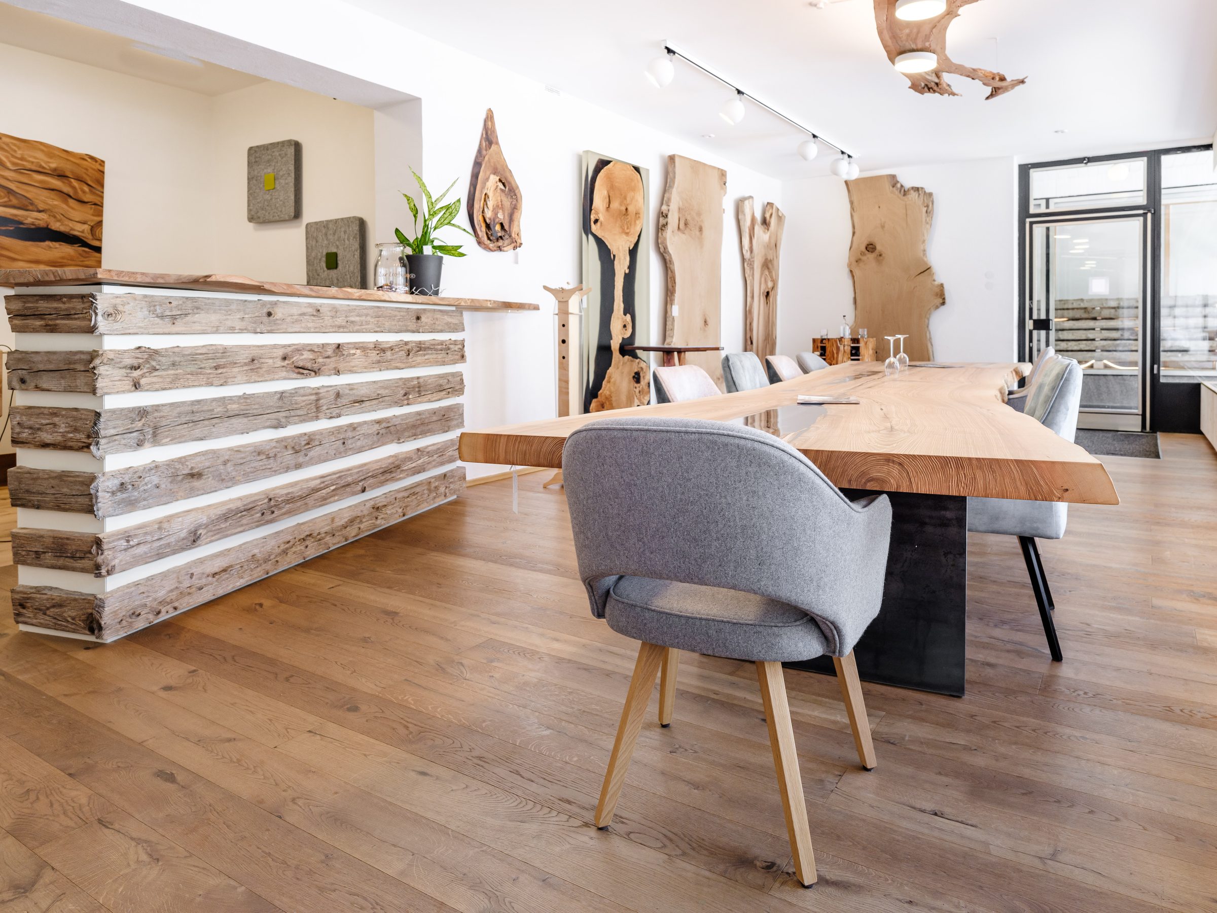 Showroom mit Altholz-Theke, langer Tafel und Holzplatten an der Wand