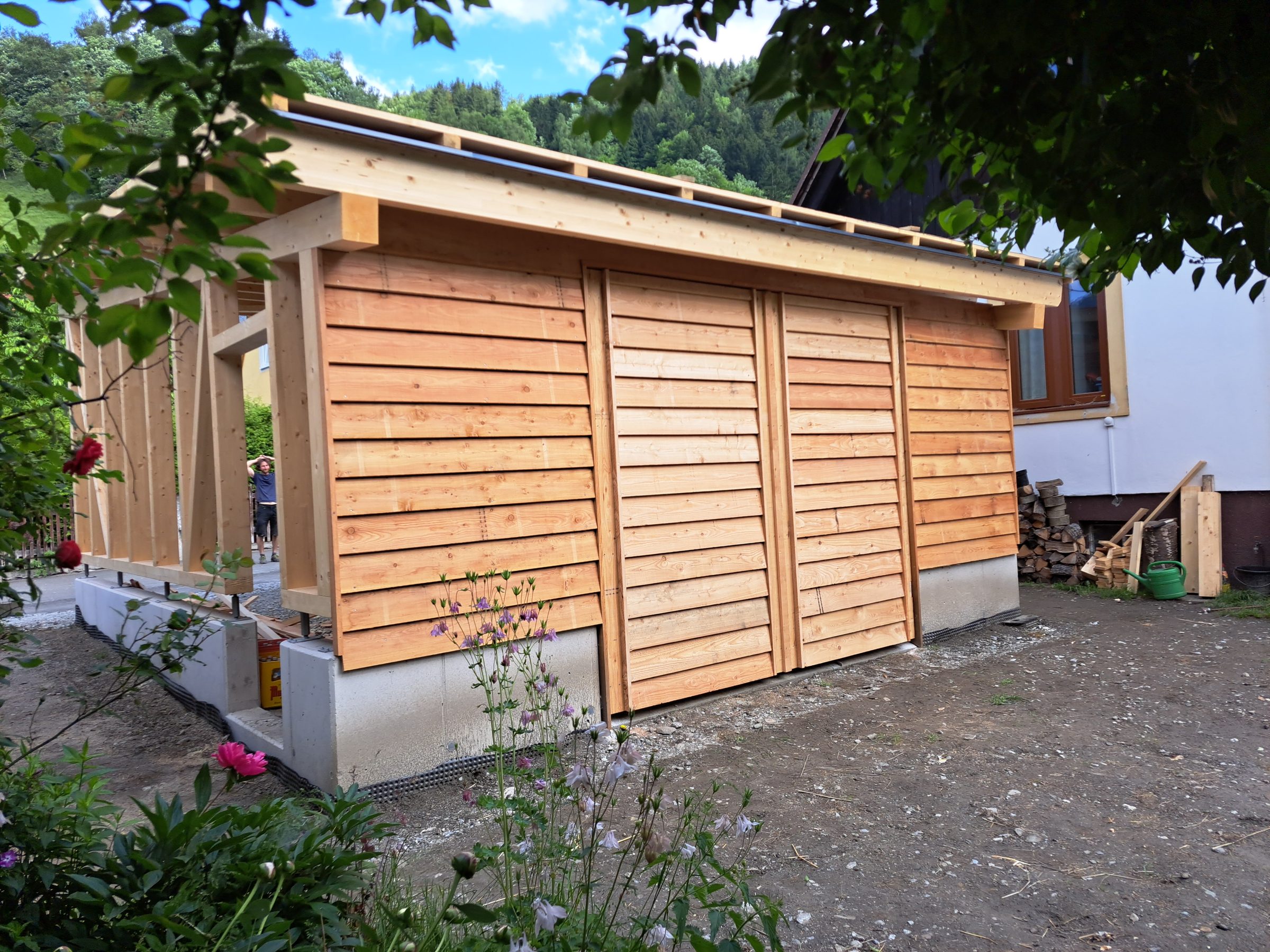 Geschlossener Holzbau mit Schiebetoren im Garten