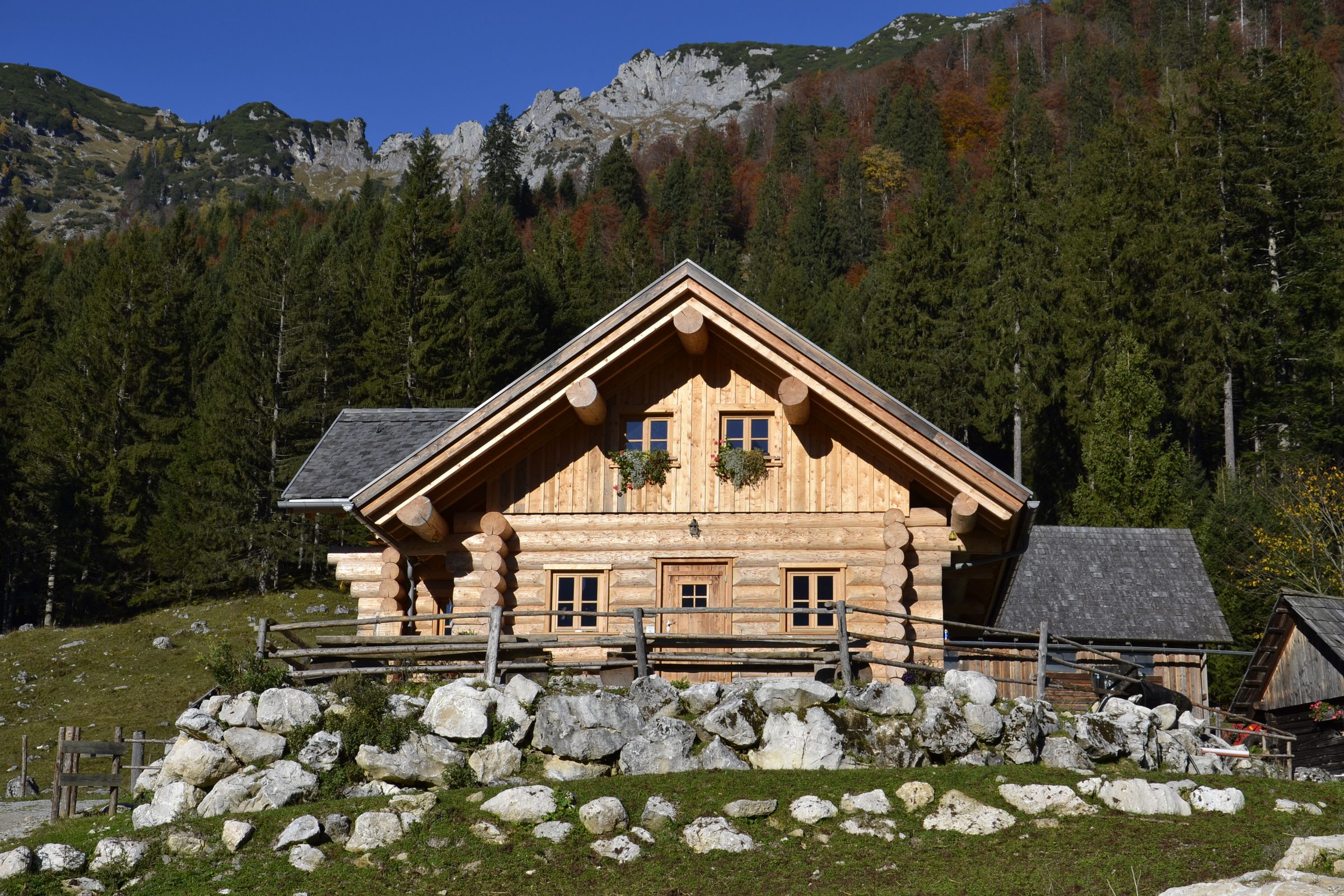 Almhütte aus Rundholz auf Bruchsteinsockel vor Felswänden