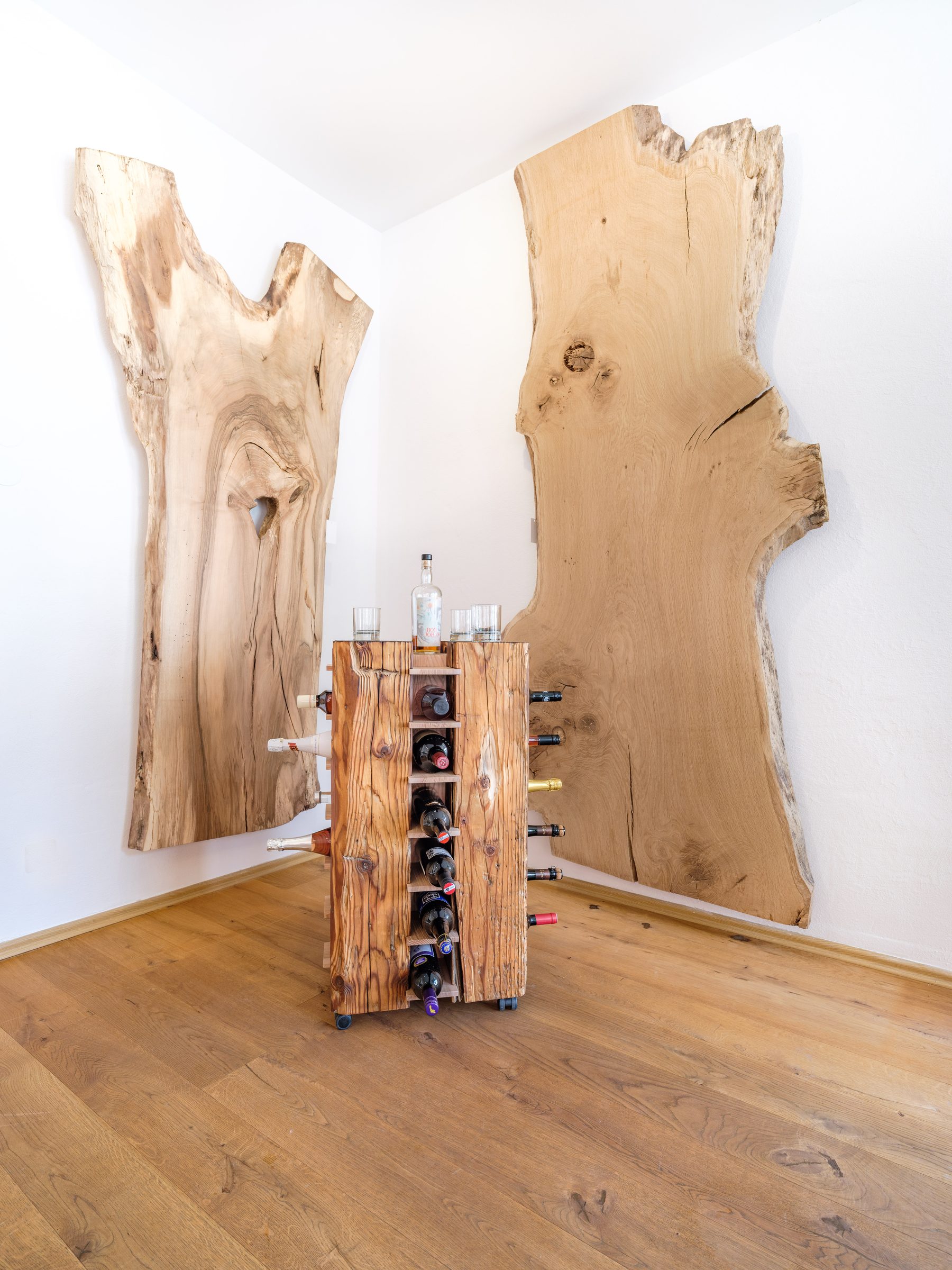 Weinregal aus Holz vor zwei großen Holzplatten an der Wand