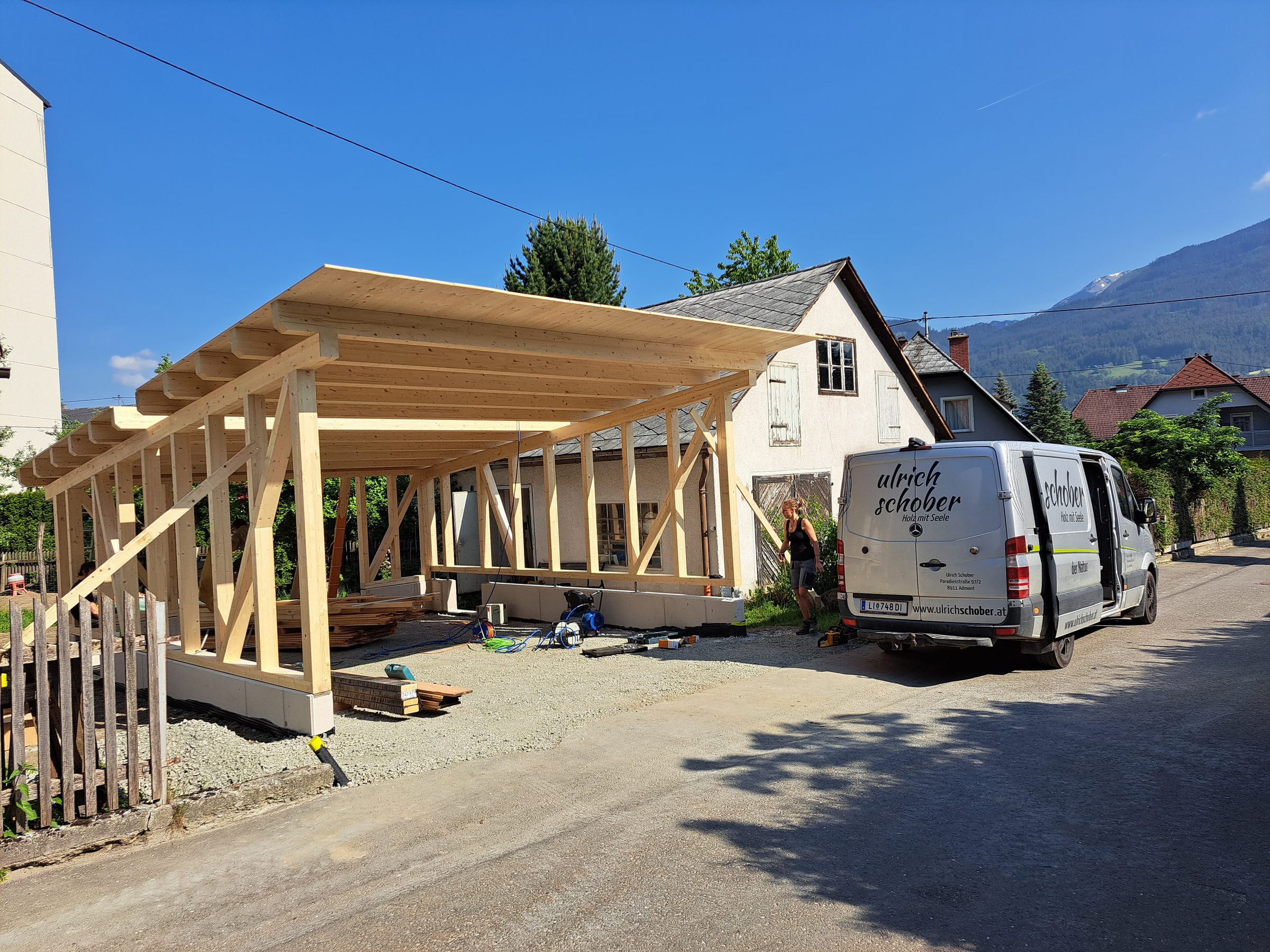 Aufgerichtetes Holztragwerk des Carports neben dem Wohnhaus