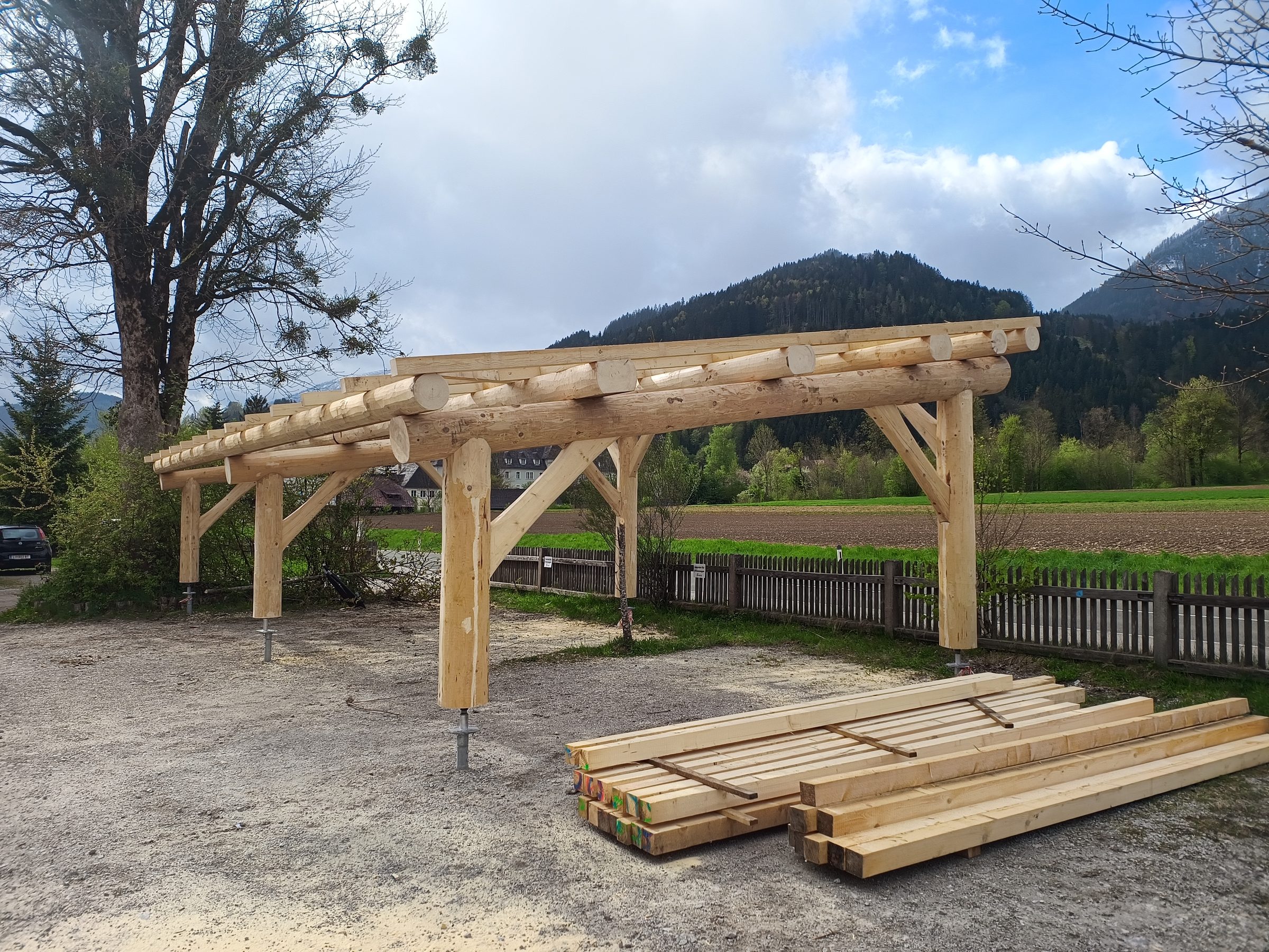 Carport aus Rundholz mit Kopfbändern vor den Bergen