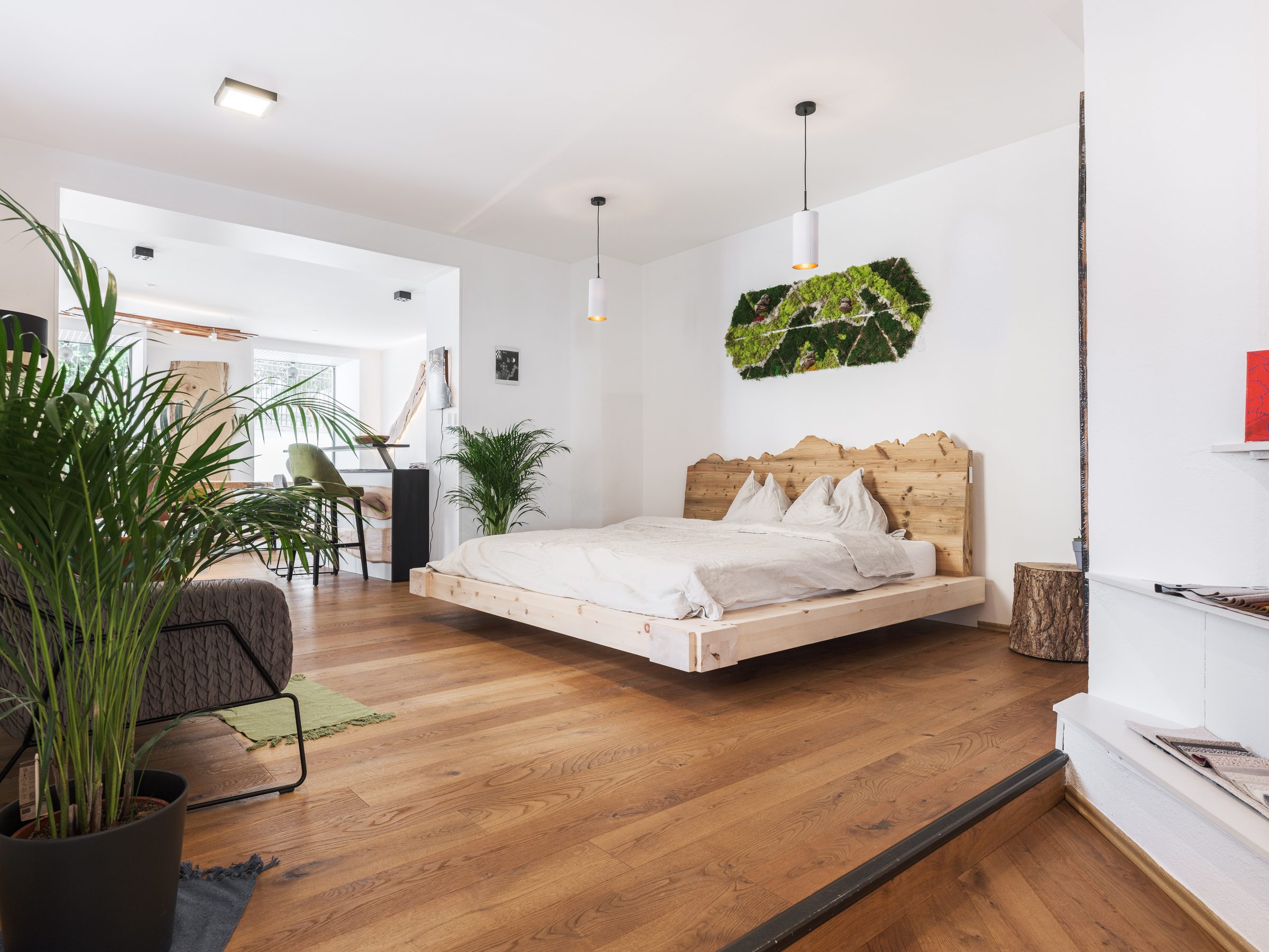 Schlafzimmer im Showroom mit Massivholzbett und Pflanzen
